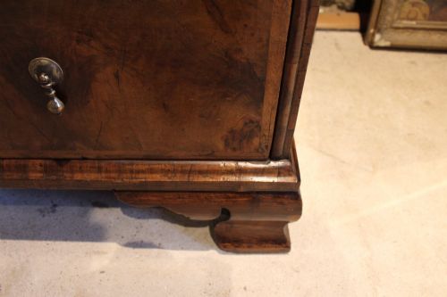 fig 5. An 18th-century George II burr walnut chest of drawers featuring two short over three long graduated drawers on bracket feet.