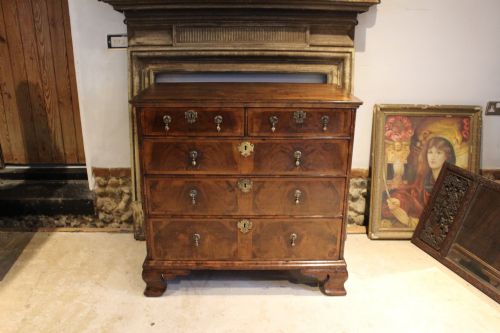 fig 6. An 18th-century George II burr walnut chest of drawers featuring two short over three long graduated drawers on bracket feet.