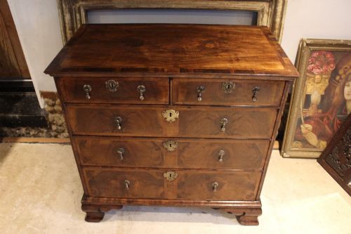 fig 7. An 18th-century George II burr walnut chest of drawers featuring two short over three long graduated drawers on bracket feet.