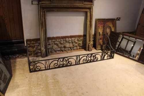 fig 2. A large dark steel fire fender featuring decorative scrolling ironwork along the front and side returns.
