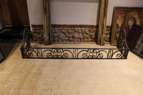 fig 6. A large dark steel fire fender featuring decorative scrolling ironwork along the front and side returns.