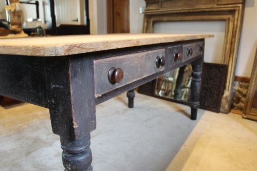 fig 1. A 19th-century pine farmhouse dining table featuring a natural scrubbed wooden top, frieze drawers with round wooden knobs, and turned dark painted legs.