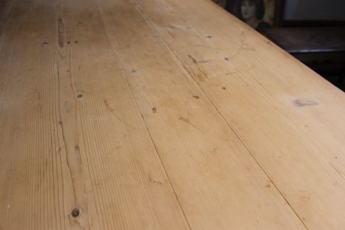 fig 4. A 19th-century pine farmhouse dining table featuring a natural scrubbed wooden top, frieze drawers with round wooden knobs, and turned dark painted legs.