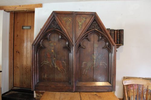 fig 1. A pair of arched dark oak architectural panels featuring carved Gothic tracery and polychrome paintings of mounted medieval knights and heraldic shields.