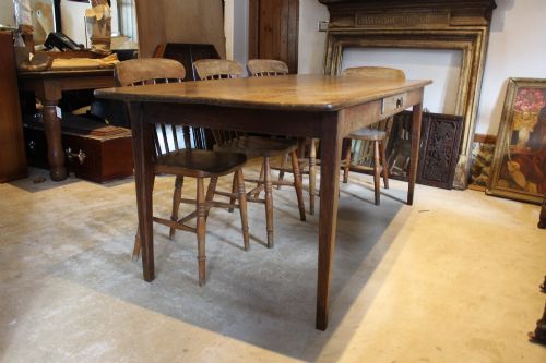 fig 1. An antique French oak refectory dining table featuring a solid two-plank top, a side frieze drawer, and square tapered legs.