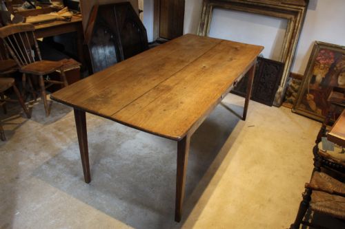fig 3. An antique French oak refectory dining table featuring a solid two-plank top, a side frieze drawer, and square tapered legs.