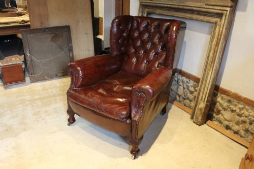 fig 3. A late Victorian deep-buttoned chestnut brown leather wingback armchair featuring brass studding, carved front legs with ball-and-claw feet, and metal castors.
