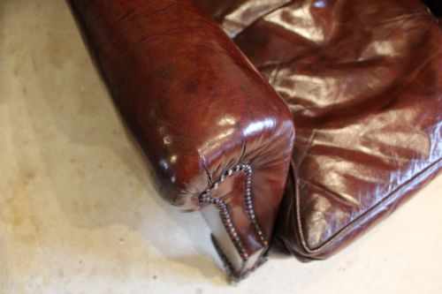 fig 5. A late Victorian deep-buttoned chestnut brown leather wingback armchair featuring brass studding, carved front legs with ball-and-claw feet, and metal castors.