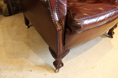 fig 8. A late Victorian deep-buttoned chestnut brown leather wingback armchair featuring brass studding, carved front legs with ball-and-claw feet, and metal castors.