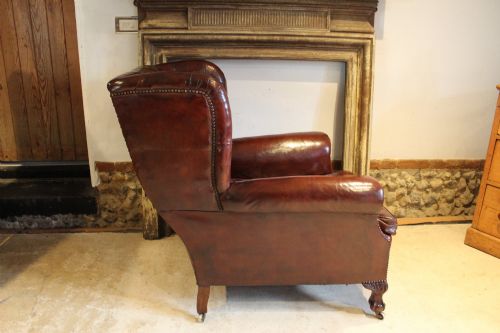 fig 9. A late Victorian deep-buttoned chestnut brown leather wingback armchair featuring brass studding, carved front legs with ball-and-claw feet, and metal castors.