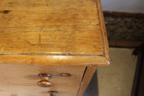 fig 5. An early Victorian honey pine dresser base featuring a central panelled cupboard door flanked by three drawers on each side with turned wooden knobs.