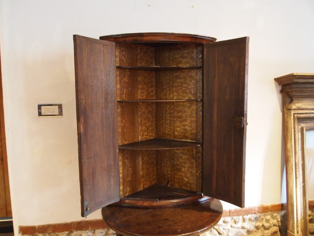 A dark walnut bowfront corner cabinet featuring two doors detailed with geometric mother of pearl inlay and brass hinges. View VIII
