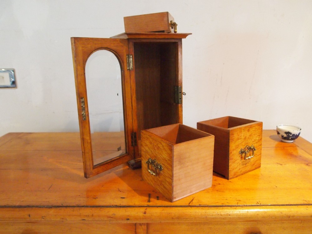A tall Victorian oak collectors chest with an arched glass door enclosing internal drawers fitted with brass handles. View VIII