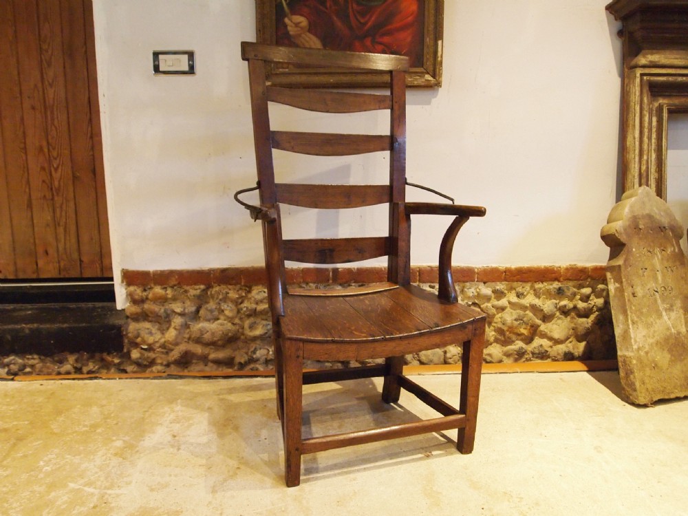 A late 18th-century George III oak and elm reclining ladderback armchair with curved arms and iron side stays.