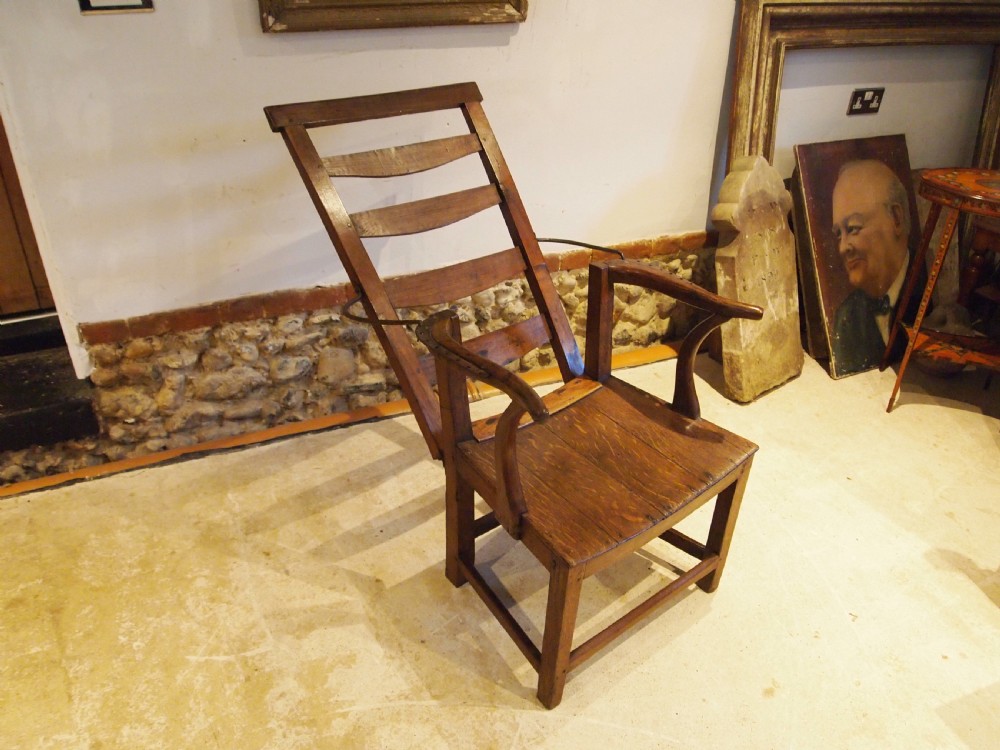 A late 18th-century George III oak and elm reclining ladderback armchair with curved arms and iron side stays. View IV