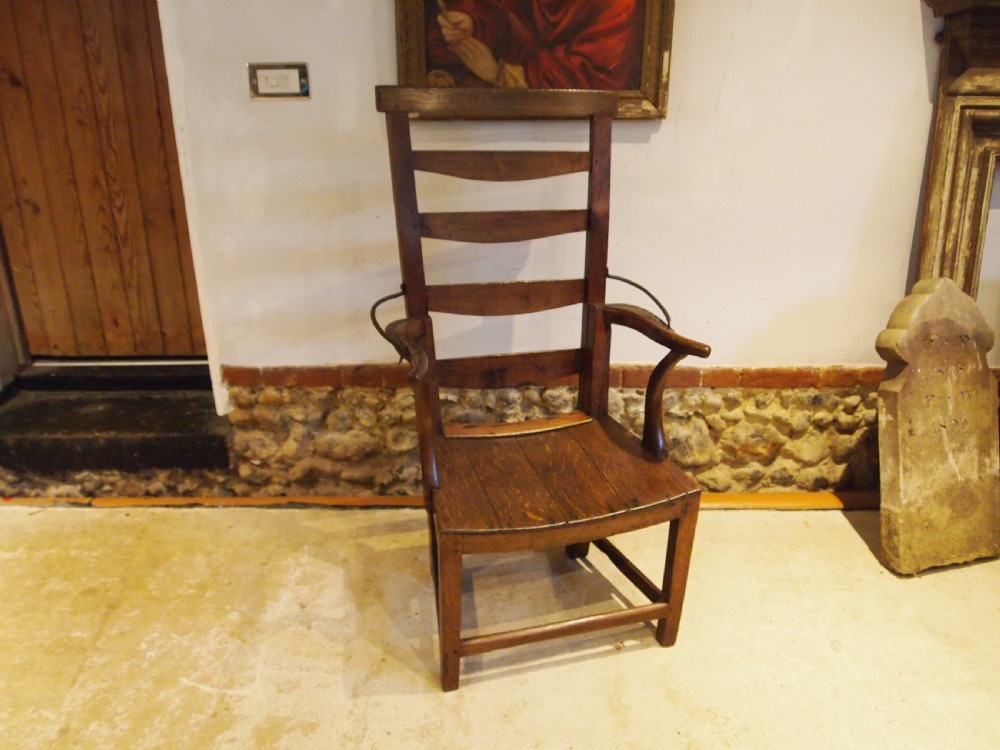 A late 18th-century George III oak and elm reclining ladderback armchair with curved arms and iron side stays. View X