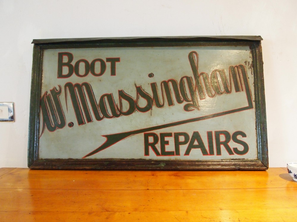 A rectangular hand-painted antique metal shop sign featuring black lettering outlined in red reading Boot W Massingham Repairs against a grey background within a dark metal frame. View III