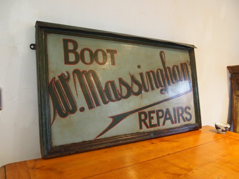 A rectangular hand-painted antique metal shop sign featuring black lettering outlined in red reading Boot W Massingham Repairs against a grey background within a dark metal frame. View XIV