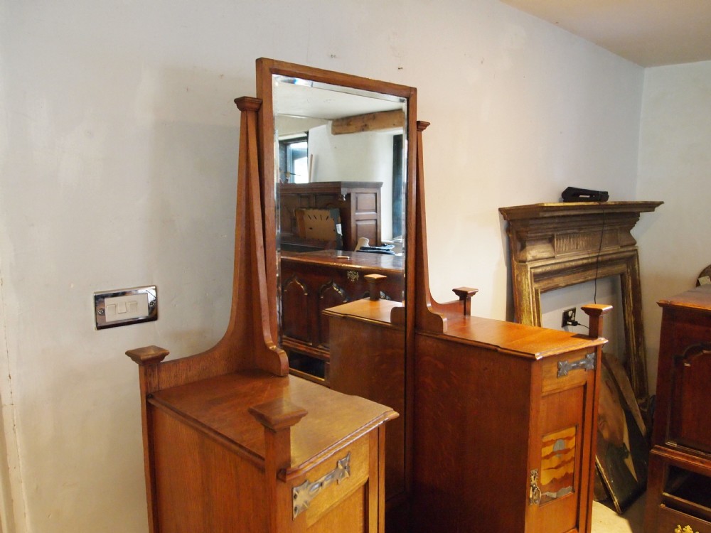 An Arts and Crafts solid oak dressing table featuring a central tall mirror flanked by two side cupboards with decorative inlaid landscape panels and metal strap hinges. View VIII