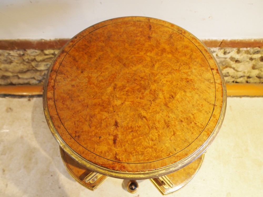 A circular Victorian burr walnut revolving library table featuring parcel gilt detailing, a turned pedestal base, and lower gallery shelves. View II