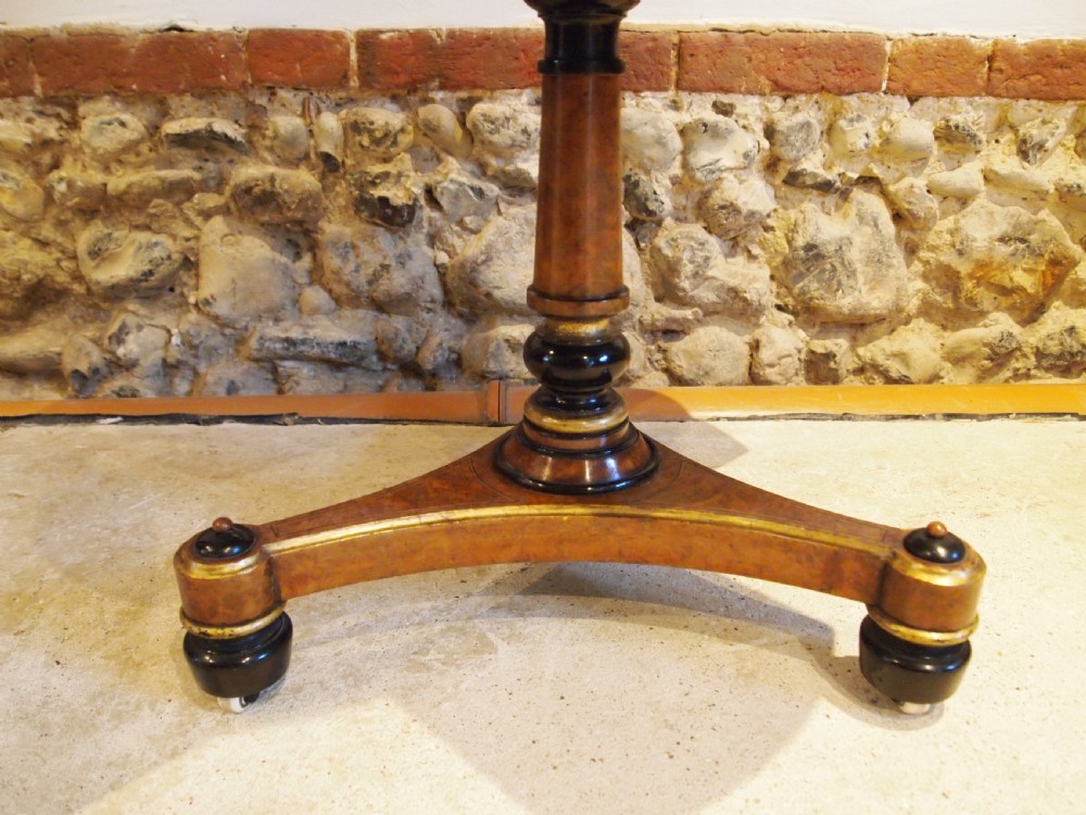 A circular Victorian burr walnut revolving library table featuring parcel gilt detailing, a turned pedestal base, and lower gallery shelves. View VII