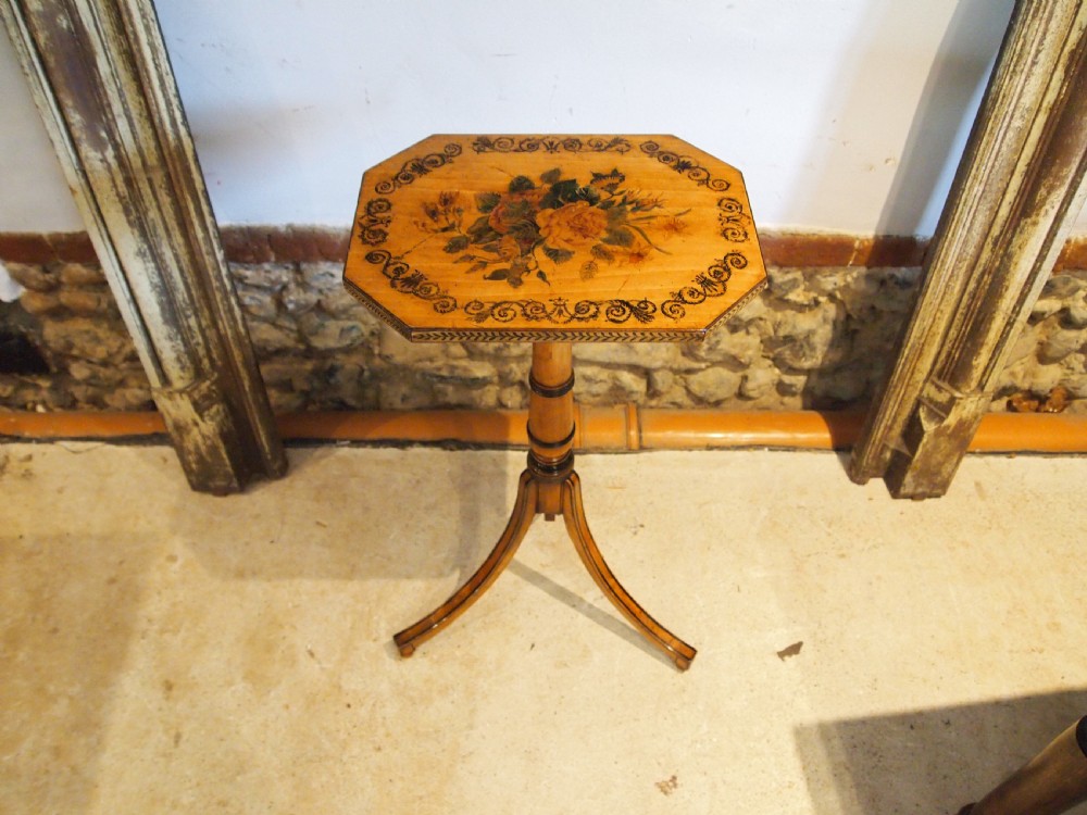 An octagonal Regency satinwood tilt-top table featuring hand-painted floral artwork on a slender turned column and tripod base.