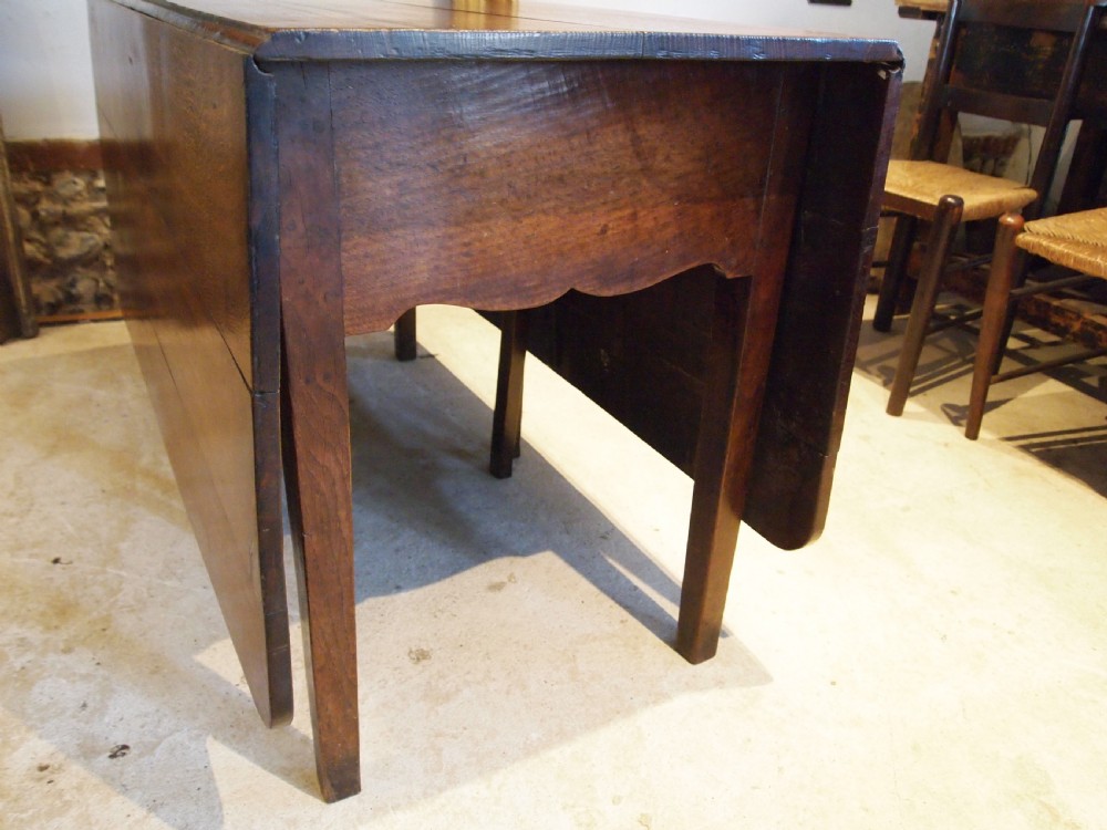 An 18th-century George III Welsh oak drop-leaf dining table with square tapered legs and a shaped apron. View III