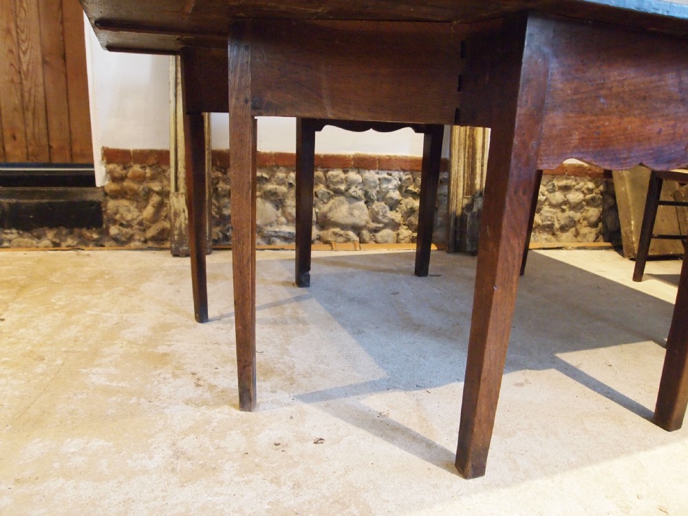 An 18th-century George III Welsh oak drop-leaf dining table with square tapered legs and a shaped apron. View VII