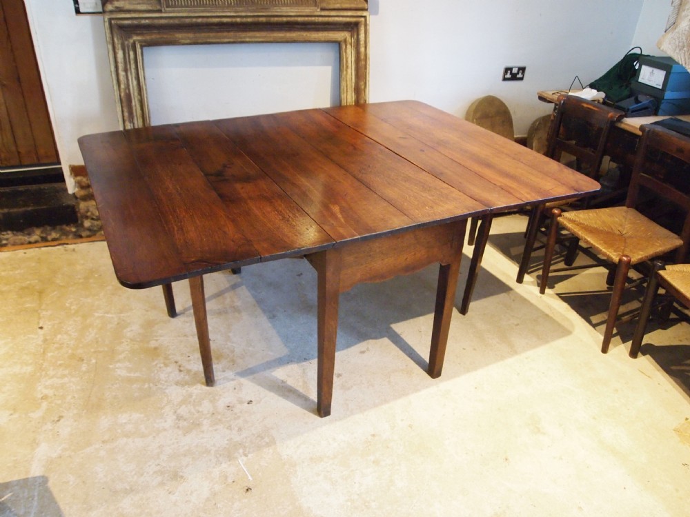 An 18th-century George III Welsh oak drop-leaf dining table with square tapered legs and a shaped apron. View IX