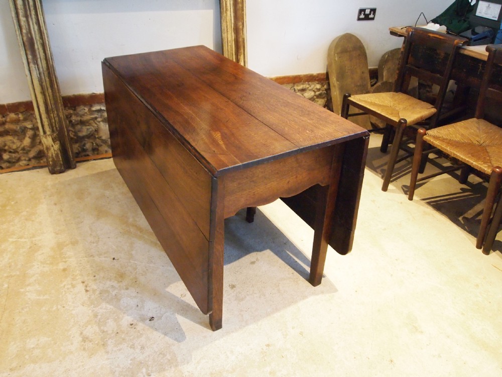 An 18th-century George III Welsh oak drop-leaf dining table with square tapered legs and a shaped apron. View X