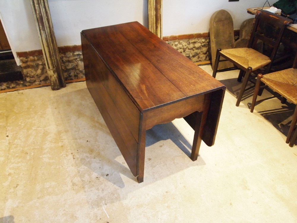An 18th-century George III Welsh oak drop-leaf dining table with square tapered legs and a shaped apron. View XI