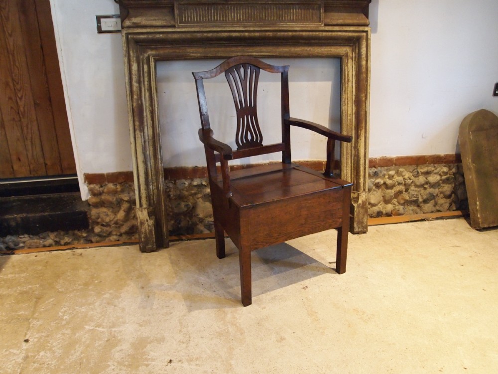 A George III Welsh oak commode armchair featuring a pierced back splat, shaped armrests, square legs, and an enclosed box seat base.