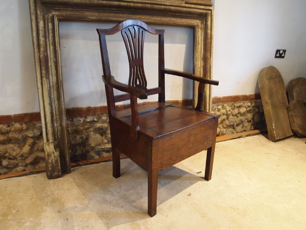 A George III Welsh oak commode armchair featuring a pierced back splat, shaped armrests, square legs, and an enclosed box seat base. View X