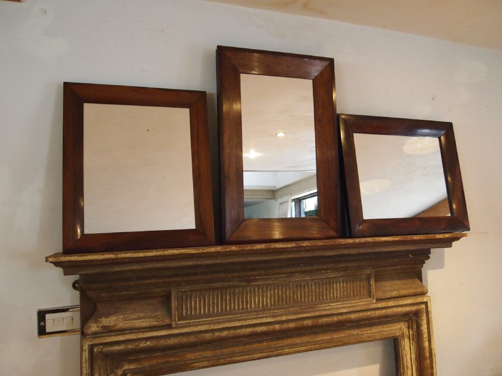 A trio of rectangular Regency period mirrors featuring dark rosewood frames with wide moulded borders.