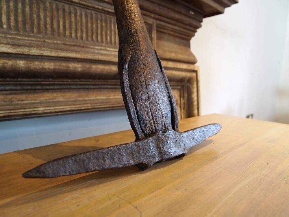 An antique nineteenth-century miners pickaxe with a dark turned wooden handle and a hand-forged iron head. View IX
