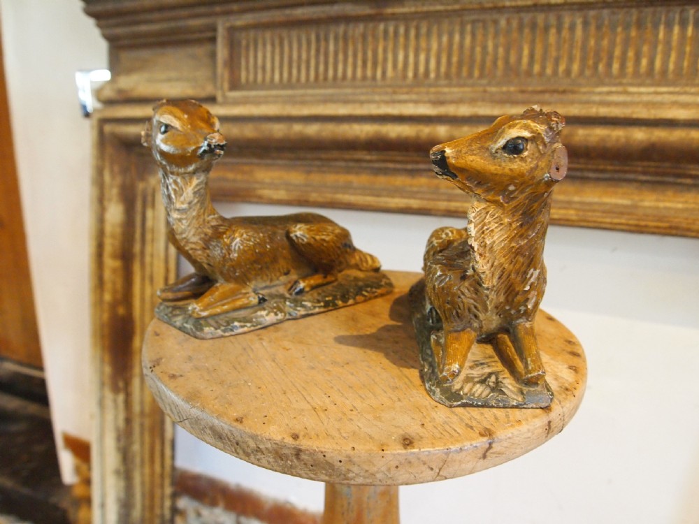 A pair of hand-carved limewood fawns in recumbent poses with detailed carved fur on integral wooden bases. View II