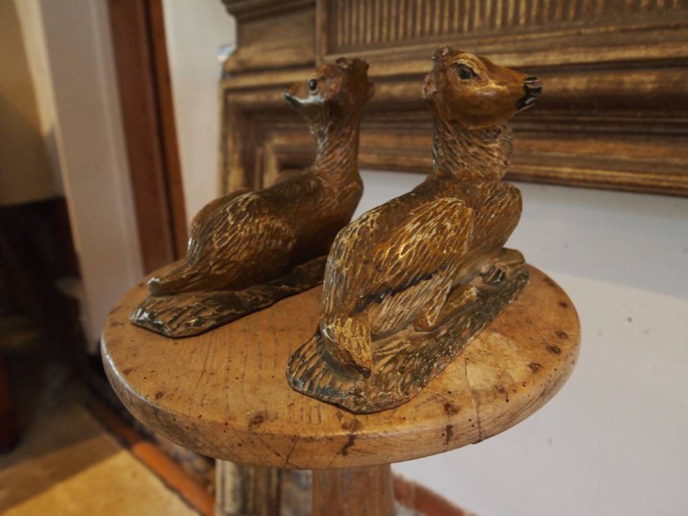 A pair of hand-carved limewood fawns in recumbent poses with detailed carved fur on integral wooden bases. View V