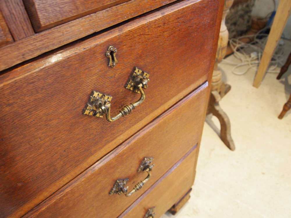 A Victorian oak chest of drawers featuring an upper gallery shelf, seven drawers with ornate brass drop handles, and planked sides. View XII