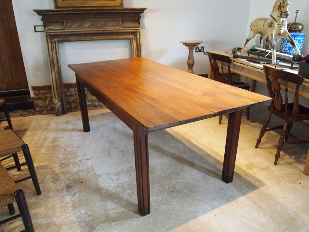 A 19th-century French cherry wood refectory dining table with a plank top and fluted square legs.