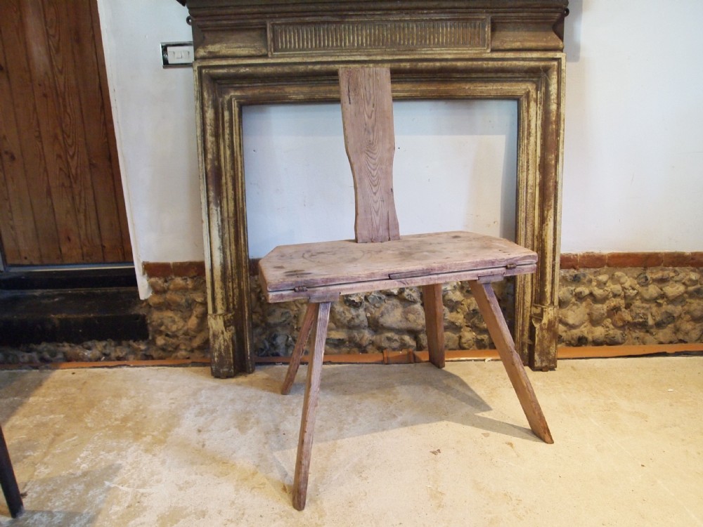 A George III primitive pine chair table featuring a tall central wooden backboard splat, flat bench seat, iron hinges, and four splayed round legs. View VIII