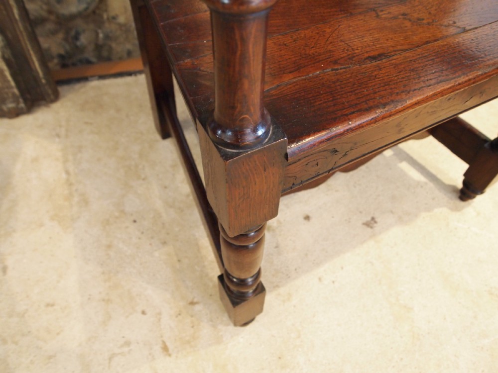 An eighteenth-century dark oak wainscot armchair featuring a panelled backrest, carved finials, turned front legs, and sturdy wooden stretchers. View VII