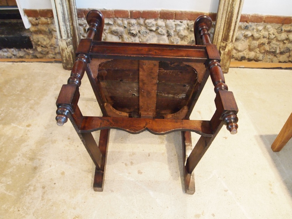 An eighteenth-century dark oak wainscot armchair featuring a panelled backrest, carved finials, turned front legs, and sturdy wooden stretchers. View VIII