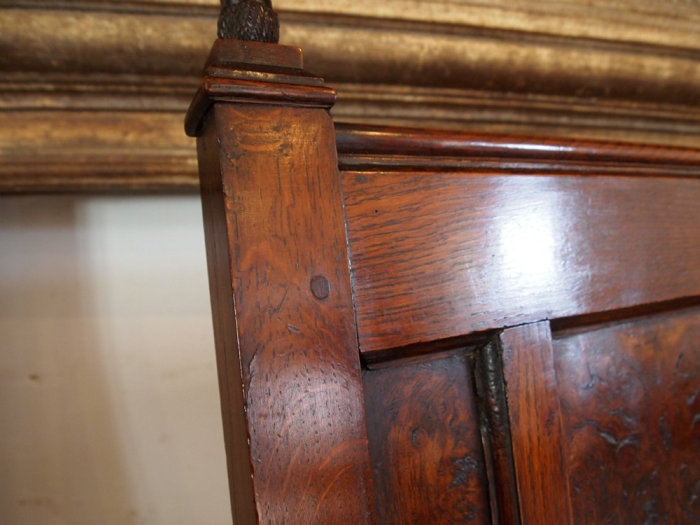 An eighteenth-century dark oak wainscot armchair featuring a panelled backrest, carved finials, turned front legs, and sturdy wooden stretchers. View XII