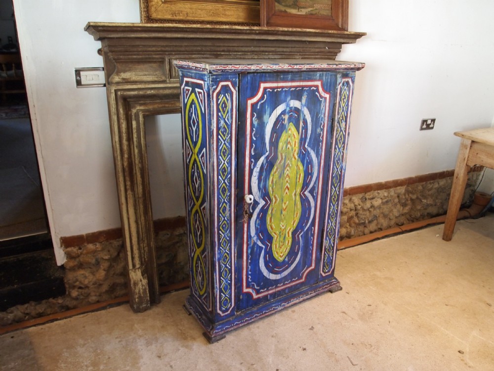 A Victorian pine single-door cupboard decorated with vibrant hand-painted blue, yellow, red, and white geometric folk art motifs. View II