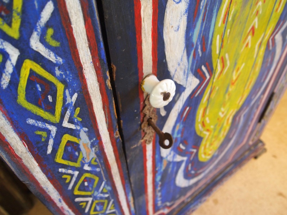 A Victorian pine single-door cupboard decorated with vibrant hand-painted blue, yellow, red, and white geometric folk art motifs. View III