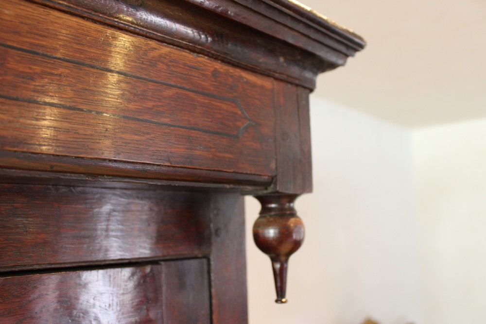 An 18th-century dark oak Welsh Cwpwrdd Deuddarn featuring a two-stage cupboard design with arched panelled upper doors, pendant drop finials, and lower drawers. View III