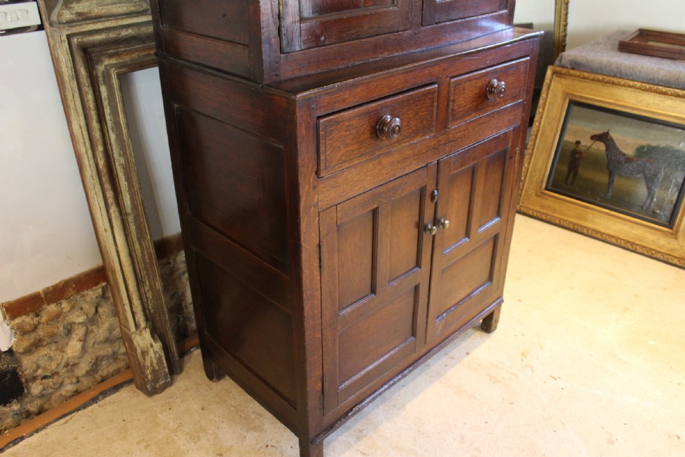 An 18th-century dark oak Welsh Cwpwrdd Deuddarn featuring a two-stage cupboard design with arched panelled upper doors, pendant drop finials, and lower drawers. View V