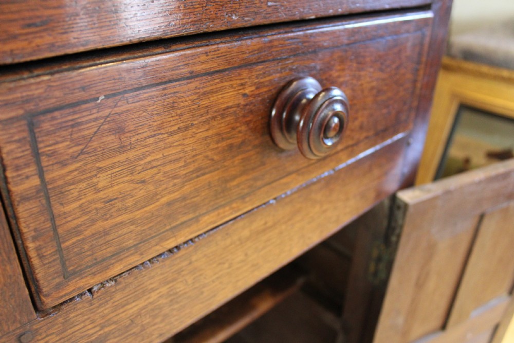 An 18th-century dark oak Welsh Cwpwrdd Deuddarn featuring a two-stage cupboard design with arched panelled upper doors, pendant drop finials, and lower drawers. View XV