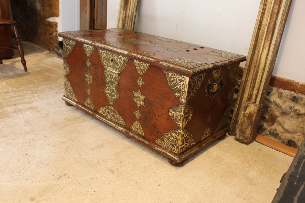 An antique warm brown teak wooden chest adorned with elaborate pierced brass plates, star-shaped metal appliques, and brass stud detailing. View III