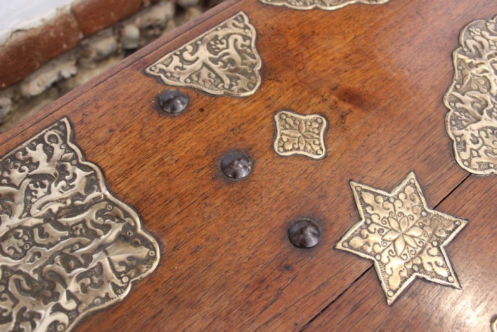 An antique warm brown teak wooden chest adorned with elaborate pierced brass plates, star-shaped metal appliques, and brass stud detailing. View VII